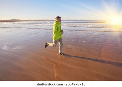 A young man in a green jacket enjoys a run along the Essaouira coastline in Morocco, where the ocean breeze invigorates the seaside atmosphere - Powered by Shutterstock