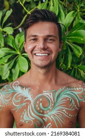 Young Man With Green And White Body Paint Art In Mexico With White Smile Against A Green Plant Background