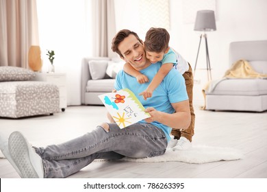 Young man and greeting card for Father's Day from his little son at home