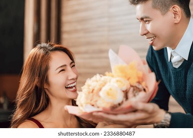 Young man greeting his girlfriend on Valentine's Day at restaurant - Powered by Shutterstock