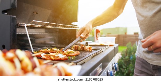 Young man grilling some kind of meats on the gas grill during lovely summer time, food concept - Shutterstock ID 2183988025