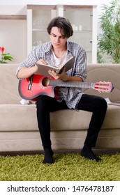 Young Man With Guitar At Home