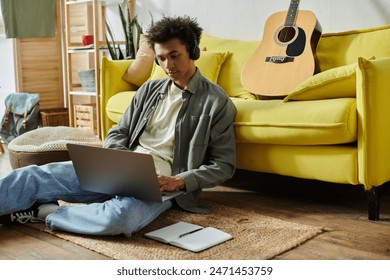 Young man with guitar and laptop on floor. - Powered by Shutterstock