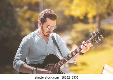 A Young Man Guitarist Is Playing Guitar At Outside In Autumun Season With Trendy Orange Colors