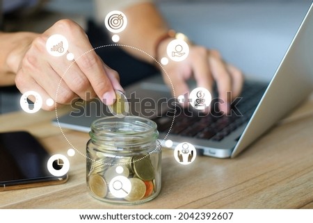 Young man hand putting money coin stack in the jar for the future, growing business, education and retirement. This concept is about saving money and investing money to grow.