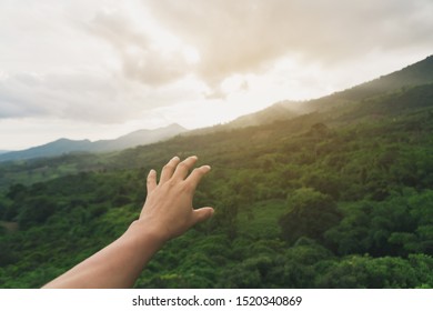 Young man hand reaching for mountains during sunset - Powered by Shutterstock