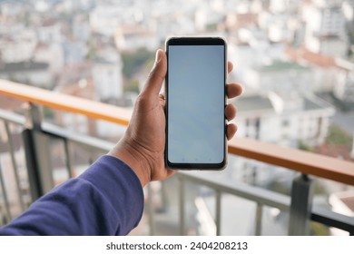 young man hand using smart phone with green screen against city buildings  - Powered by Shutterstock