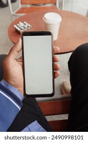 young man hand using smart phone with white screen at cafe 