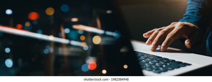 young man hand working on a laptop, bokeh blurred at night For text copy space, image size horizontal