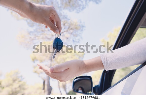 Young man handing over the keys to a car wearing a\
protective mask