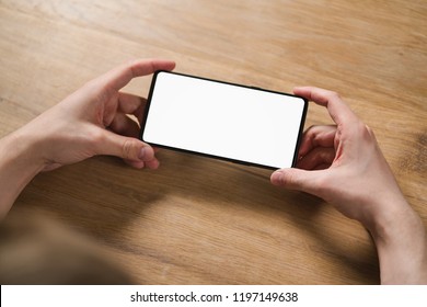 Young Man Hands Holding Smartphone With Blank White Screen In Landscape Mode