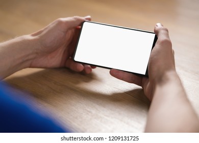 Young Man Hands Holding Smartphone With Blank White Screen In Landscape Mode