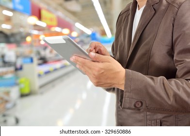 Young Man Hands holding Tablet or Mobile Device in Supermarket or Hypermarket store as Digital environment Working. Selective Focus on Right Pointer Finger or Trigger Finger.