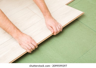 Young man hands laying light color laminate on green natural wood fiber insulation board. Flooring installation on fibreboard underlay. Repair work of home. Renovation process. Closeup.  - Shutterstock ID 2099599297