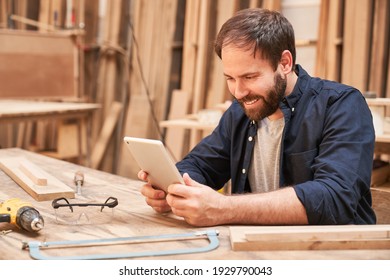 Young Man As A Handyman Reads Message On Tablet Computer In Carpentry