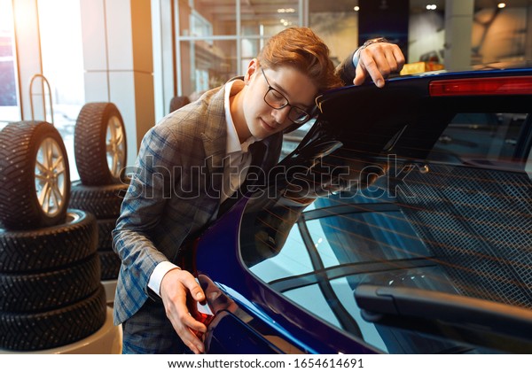 young man\
has been waiting for his broken car. close up photo. estrong warm\
feeling and emotion, guy fell in love . madness, craziness.date\
with a car. love at first\
sight
