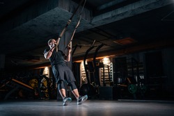 young man has crossfit workout with trx in modern gym, a man in a gym holding a rope, a Sports & Recreation Photo by Goami