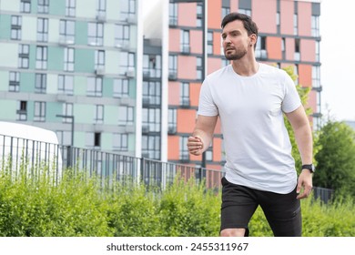 A young man has jogging or race walking in a modern residential area with colorful buildings and parkland on a summer morning on a quiet street. The concept of physical training as a healthy lifestyle - Powered by Shutterstock