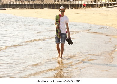 young man with hat strolling down the beach. Summer evening