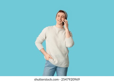 Young man in hat using mobile phone on blue background