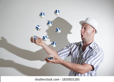 A young man in a hat and a white-blue striped shirt juggles balls on a white background.