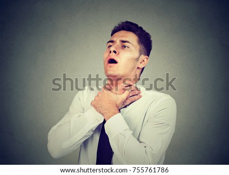 Young man having asthma attack or choking can't breath suffering from respiration problems isolated on gray background  