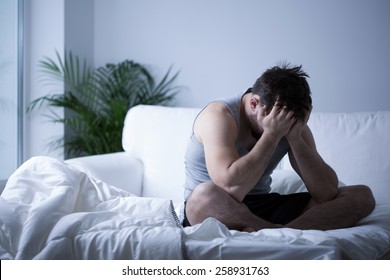 Young man having depression sitting on the bed