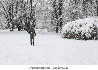 Young man having fun making snowball in winter snowy season in city park covered hill, holiday vacation weekend, enjoying spending time together
