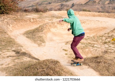 Young man having fun while riding skateboard on the mountain bike track
