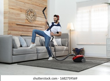 Young Man Having Fun While Vacuuming At Home