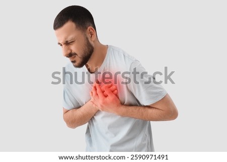 Young man having heart attack on light background
