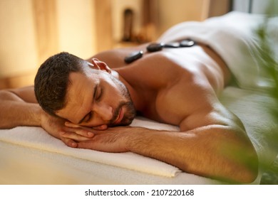 Young Man Having A Hot Stone Lastone Massage At Spa