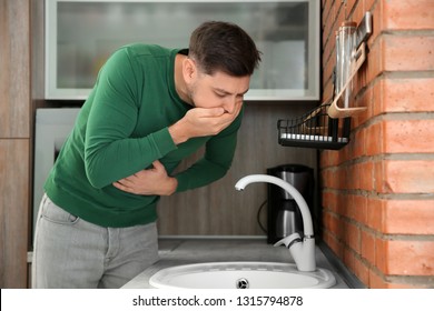 Young man having nausea in kitchen. Feeling sick