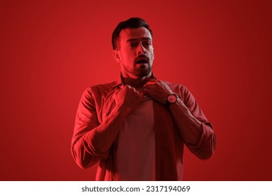 Young man having panic attack on red background