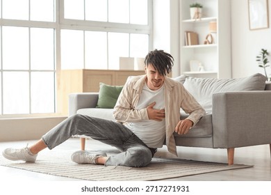 Young man having panic attack near sofa at home