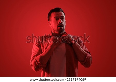 Young man having panic attack on red background