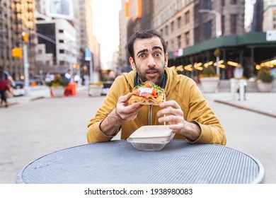 Young Man Having Pizza Snack Outdoors, Sitting On The Table, Showing Emotions. MIddle Eastern Adult. Wide Angle Shot