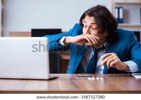 Young man having problems with narcotics at workplace 
