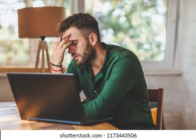 Young man having stressful time working on laptop