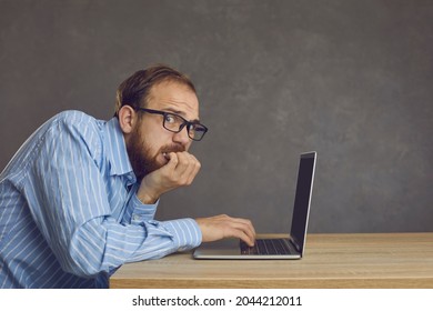 Young Man Having Trouble At Work. Scared Stressed Office Manager Sitting At Table With Laptop Computer, Biting Fingernails And Looking At Camera. Concept Of Problem, Mistake, Error, Or Forgot Password