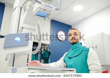 Image, Stock Photo Young man having x-ray shot of broken hand in x ray room in modern clinic. Patient wearing in protect lead apron