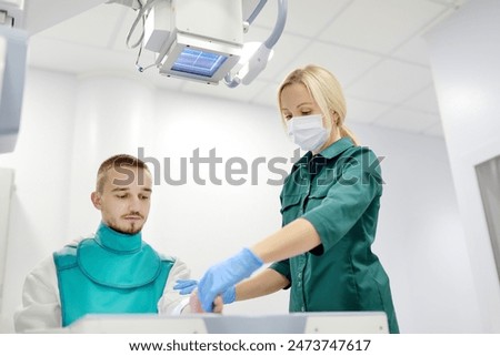 Similar – Image, Stock Photo Young man having x-ray shot of broken hand in x ray room in modern clinic. Patient wearing in protect lead apron
