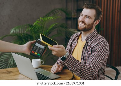 Young man he wear shirt hold wireless bank payment terminal cell phone process acquire credit card payments sit at table in coffee shop cafe rest in free time Freelance mobile office business concept - Shutterstock ID 2183971301