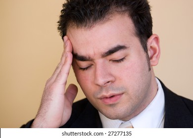 Young Man With A Headache. He Might Be Experiencing Intense Stress Over A Time Of Economic Downturn Or Other Financial Hardship.