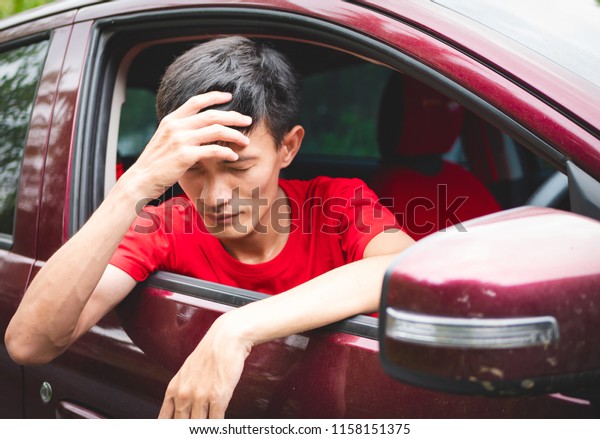 Young man headache migraine in red car outdoor,\
Asian young age with red\
T-shirt.