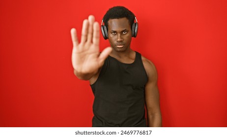 Young man with headphones extends hand against vivid red isolated background. - Powered by Shutterstock