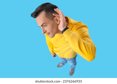 Young man with hearing problem on blue background