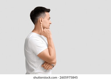 Young man with hearing problem on light background