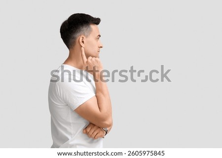 Young man with hearing problem on light background