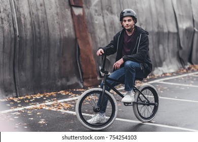 young man in helmet riding bmx bicycle and smiling at camera on street - Powered by Shutterstock